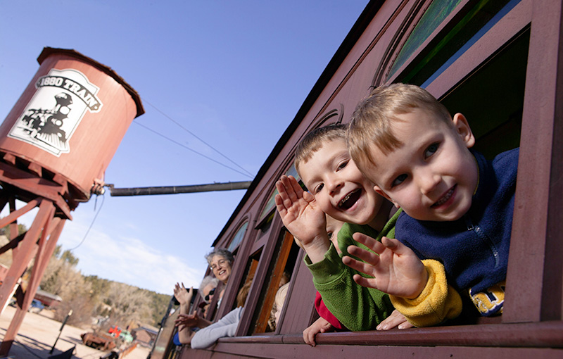 Kids smiling and waving out of train window, with water tower in the background