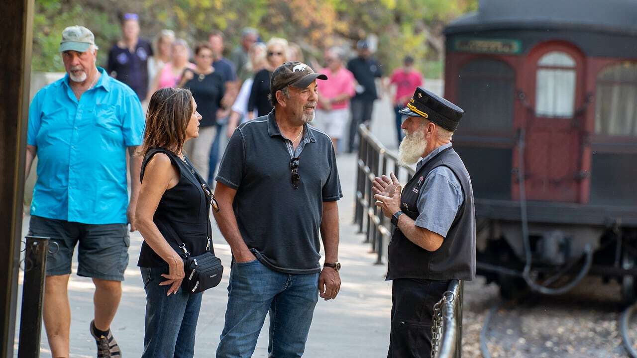 A couple engaging with a conductor at the 1880 Train. 