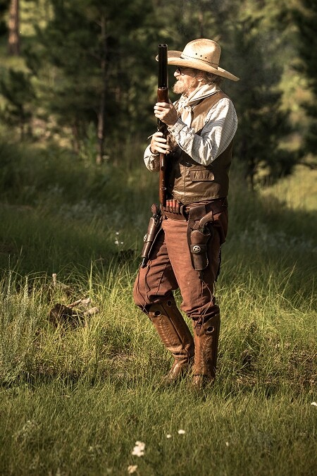 Old West gunfighter in period costume holding a rifle in a Black Hills forest clearing