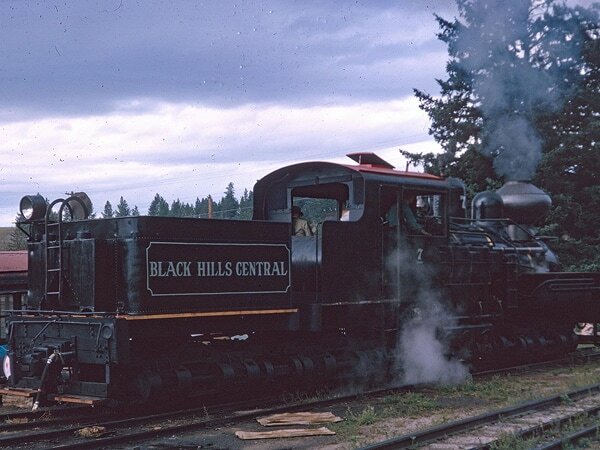 Vintage color photograph of Black Hills Central steam locomotive No. 7 at the depot, with steam rising, circa 1960s–70s